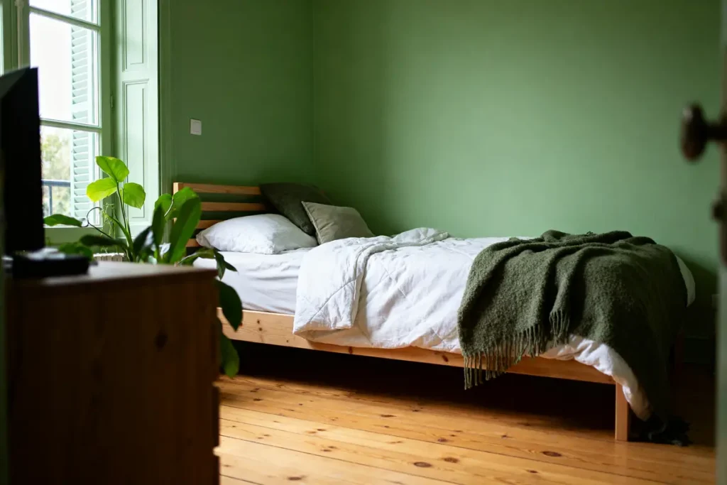 Chambre verte et bois avec lit, plante, parquet et décoration naturelle sans prétention