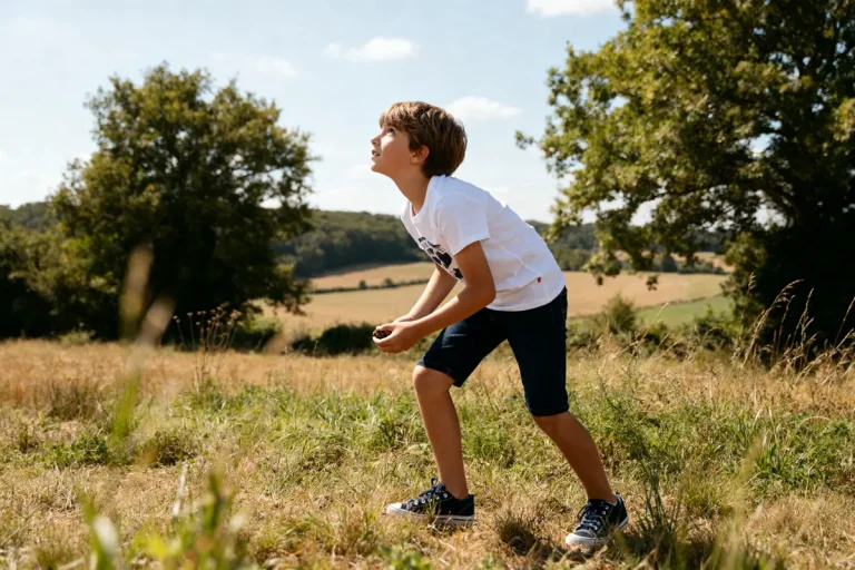Garçon debout dans un champ verdoyant sous le soleil interroge sur taille s quel age