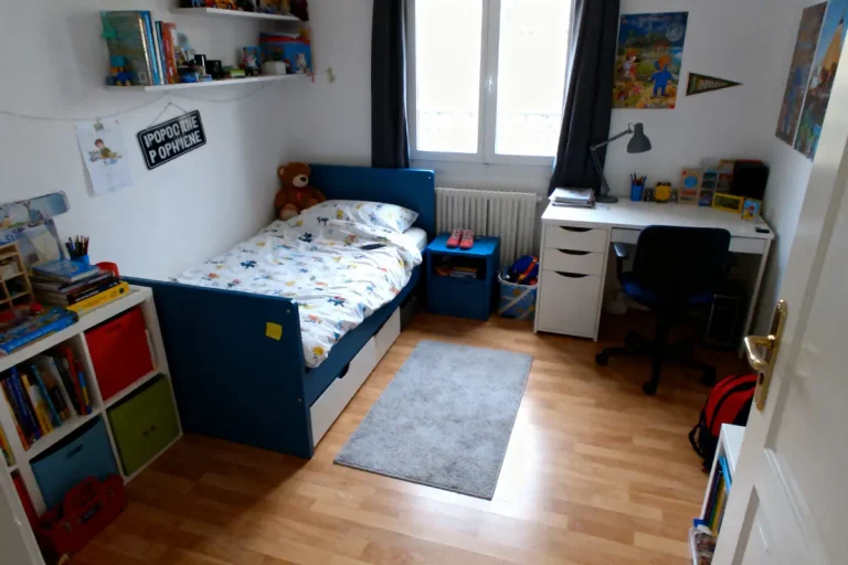 Chambre d'enfant organisée avec lit, bureau, étagères pleines de livres et jouets, tapis gris, fenêtre.